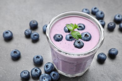 Photo of Glass of blueberry smoothie with mint and fresh berries on grey table