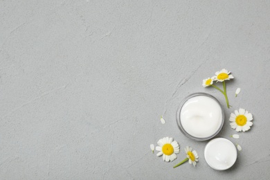 Cosmetic products and chamomiles on grey table, flat lay. Space for text