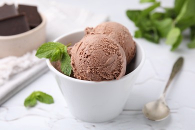 Photo of Bowl with tasty chocolate ice cream and mint leaves on white table, closeup
