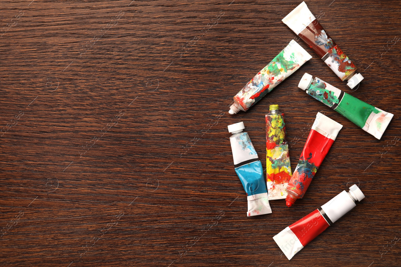 Photo of Tubes with oil paints on wooden table, flat lay. Space for text