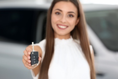 Saleswoman with car key standing in salon