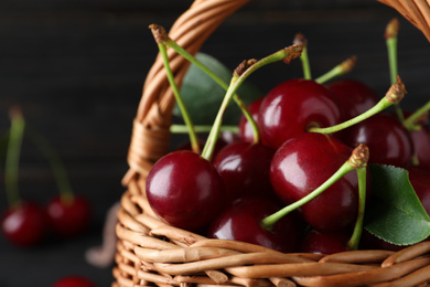 Photo of Basket with delicious sweet cherries on dark background, closeup