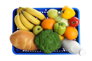 Shopping basket with grocery products on white background, top view