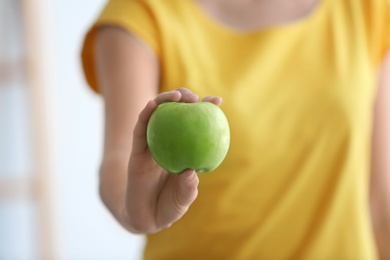 Photo of Woman holding ripe green apple on blurred background, closeup