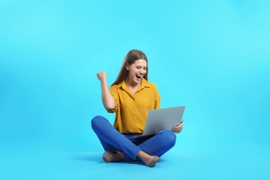 Photo of Emotional young woman with laptop celebrating victory on color background