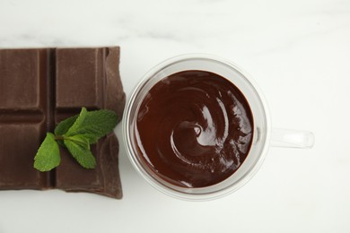 Photo of Glass cup of delicious hot chocolate, chunk and fresh mint on white marble table, flat lay