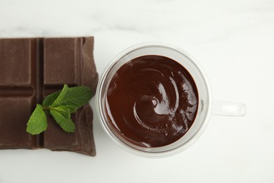 Glass cup of delicious hot chocolate, chunk and fresh mint on white marble table, flat lay