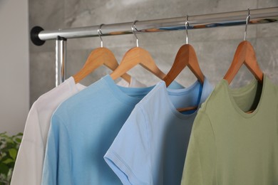 Photo of Different clean T-shirts hanging on rack indoors