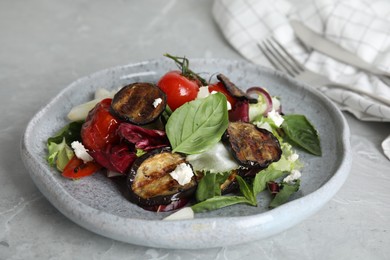 Photo of Delicious salad with roasted eggplant, basil and cheese served on grey marble table