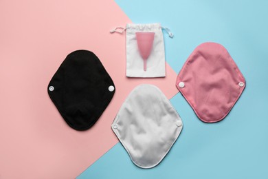 Photo of Reusable cloth pads and menstrual cup on color background, flat lay
