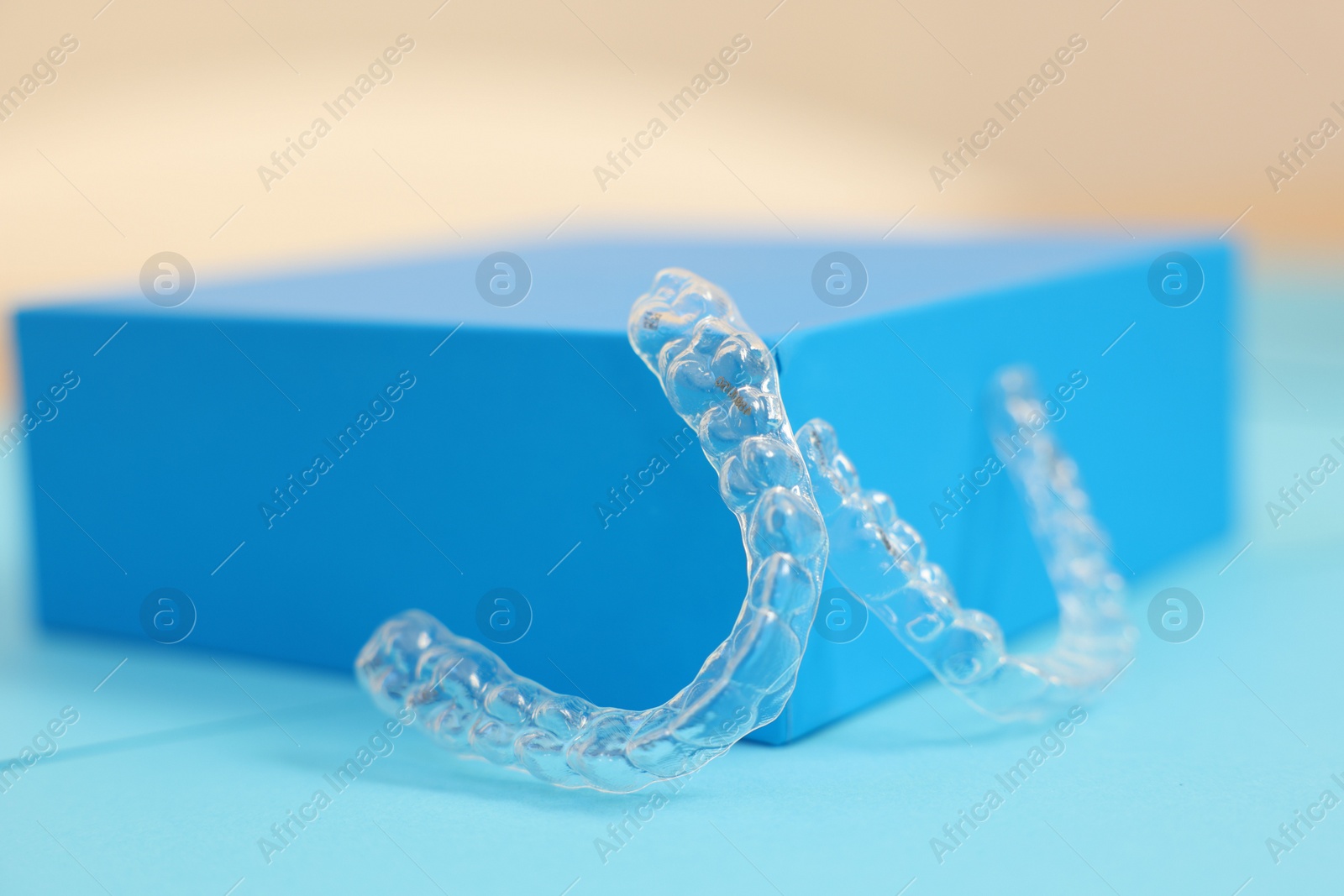 Photo of Transparent dental aligners on color background, closeup