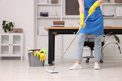 Photo of Cleaning service worker washing floor with mop, closeup. Bucket with supplies in office
