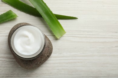 Photo of Jar of organic cream, spa stone and aloe on white wooden table, flat lay. Space for text