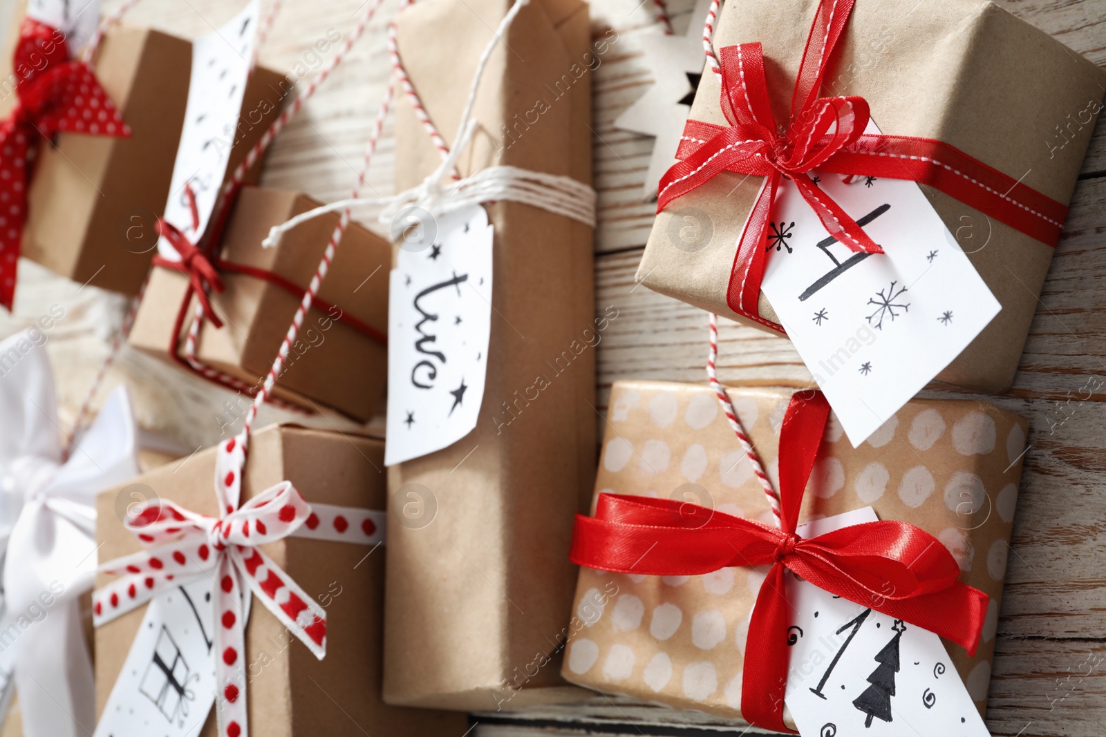 Photo of Gift boxes hanging on white wooden wall, closeup. Christmas advent calendar