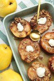 Tasty baked quinces with nuts and cream cheese in dish on table, flat lay