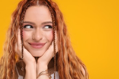 Beautiful young hippie woman on orange background, closeup. Space for text