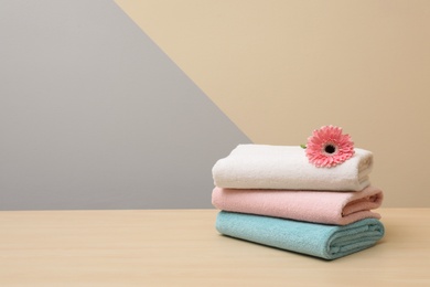 Photo of Stack of fresh towels with flower on table. Space for text