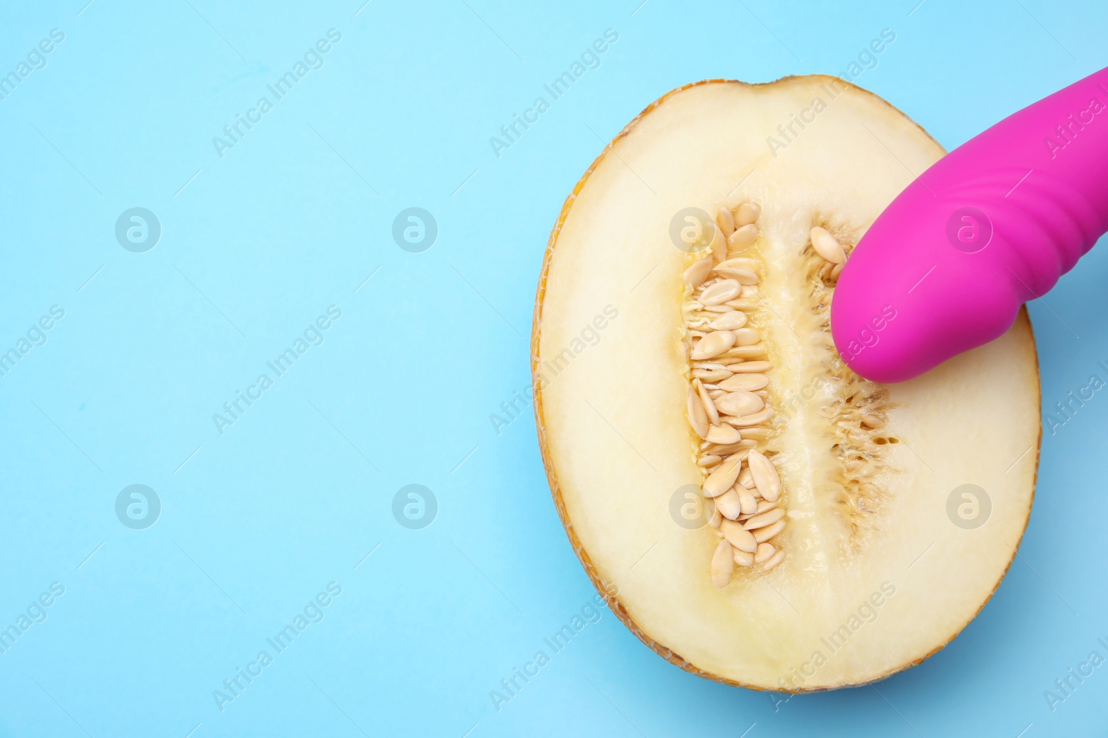 Photo of Half of melon and purple vibrator on blue background, flat lay with space for text. Sex concept