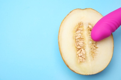 Photo of Half of melon and purple vibrator on blue background, flat lay with space for text. Sex concept