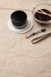 Photo of Eyebrow henna and tools on crumpled paper. Space for text