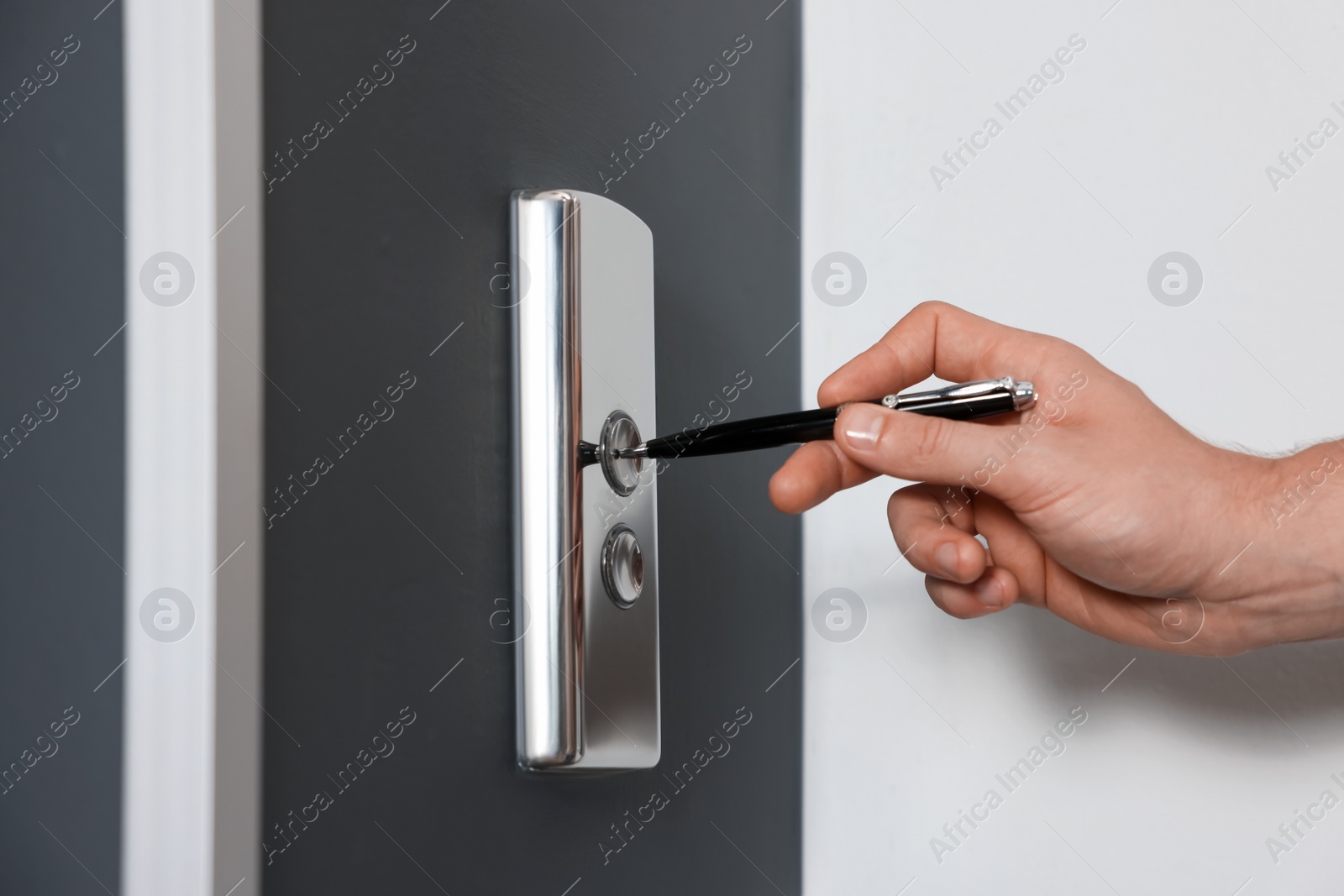 Photo of Man using pen to press elevator call button, closeup. Protective measure