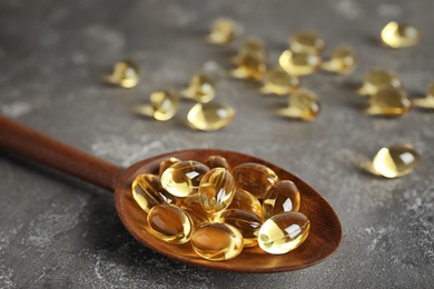 Photo of Spoon with cod liver oil pills on table, closeup