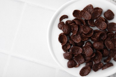 Photo of Breakfast cereal. Chocolate corn flakes and milk in bowl on white tiled table, top view. Space for text