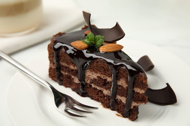 Photo of Piece of tasty homemade chocolate cake with mint and almonds on plate, closeup