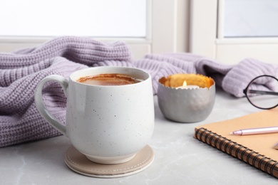 Composition with cup of hot chocolate and notebook on windowsill. Winter drink