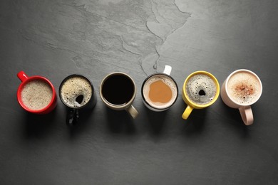 Photo of Many cups with different aromatic coffee on black table, flat lay