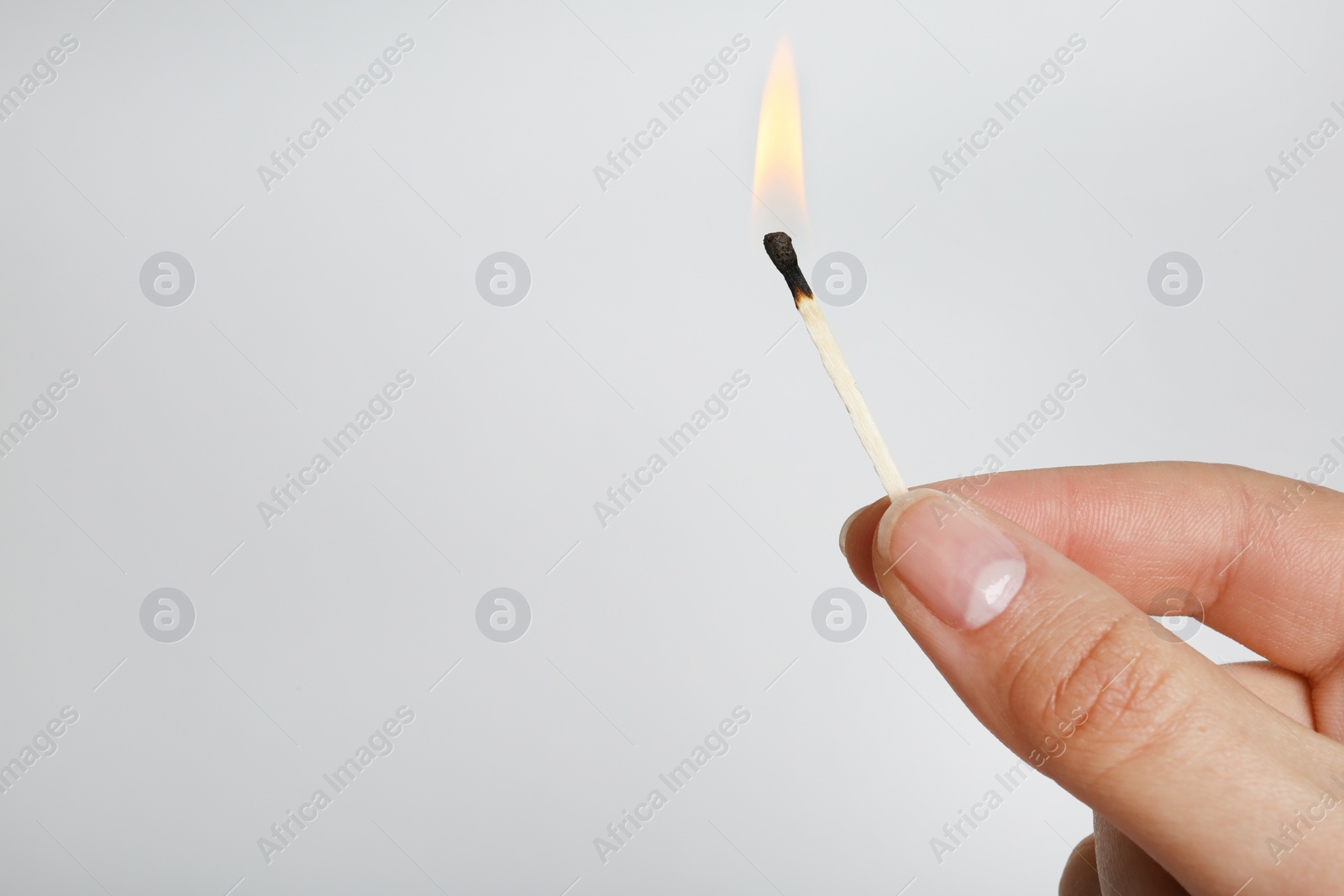 Photo of Woman holding burning match on grey background, space for text