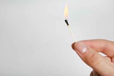 Photo of Woman holding burning match on grey background, space for text