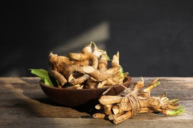 Photo of Fresh horseradish roots and leaf on wooden table, closeup