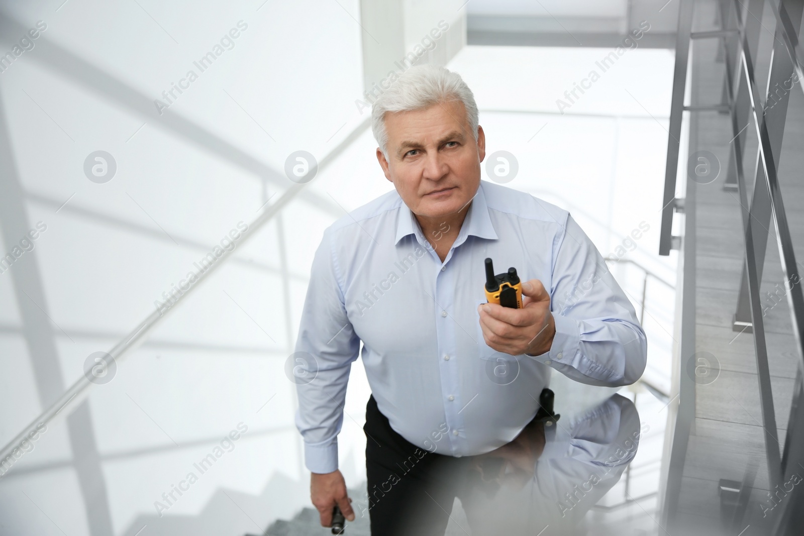 Photo of Professional security guard with portable radio set on stairs