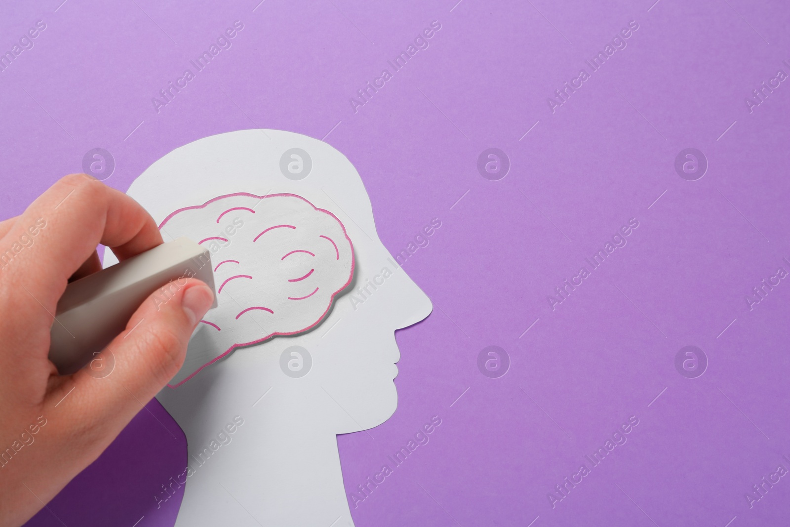 Photo of Woman erasing brain on human head paper cutout on violet background, top view with space for text. Dementia concept