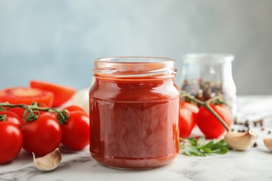 Composition with jar of tasty tomato sauce on table against grey background