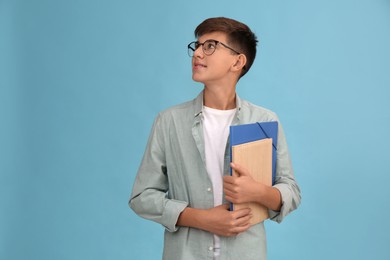 Photo of Teenage student with glasses and stationery on turquoise background