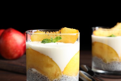 Photo of Tasty peach dessert with yogurt and chia seeds served on wooden table, closeup