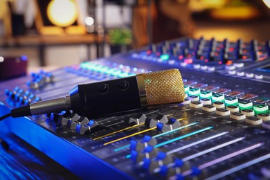 Photo of Microphone on professional mixing console in radio studio, closeup