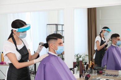 Professional stylist working with client in salon. Hairdressing services during Coronavirus quarantine