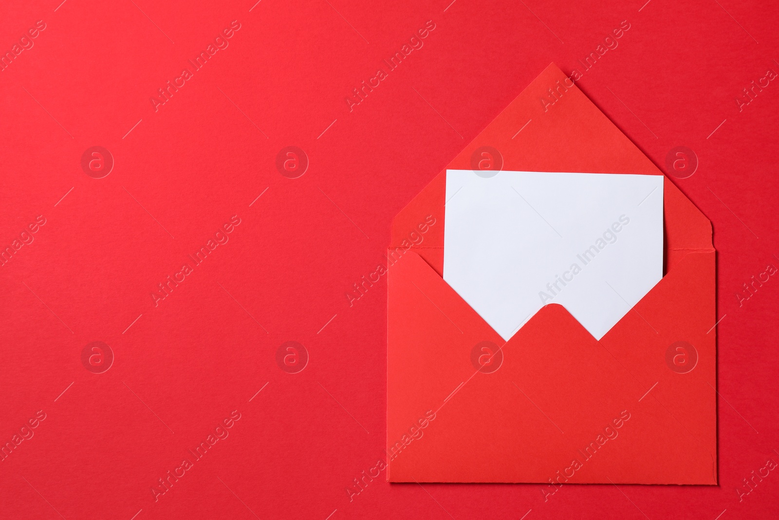 Photo of Letter envelope with card on red background, top view. Space for text