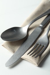 Photo of Stylish cutlery set and napkin on white table, closeup