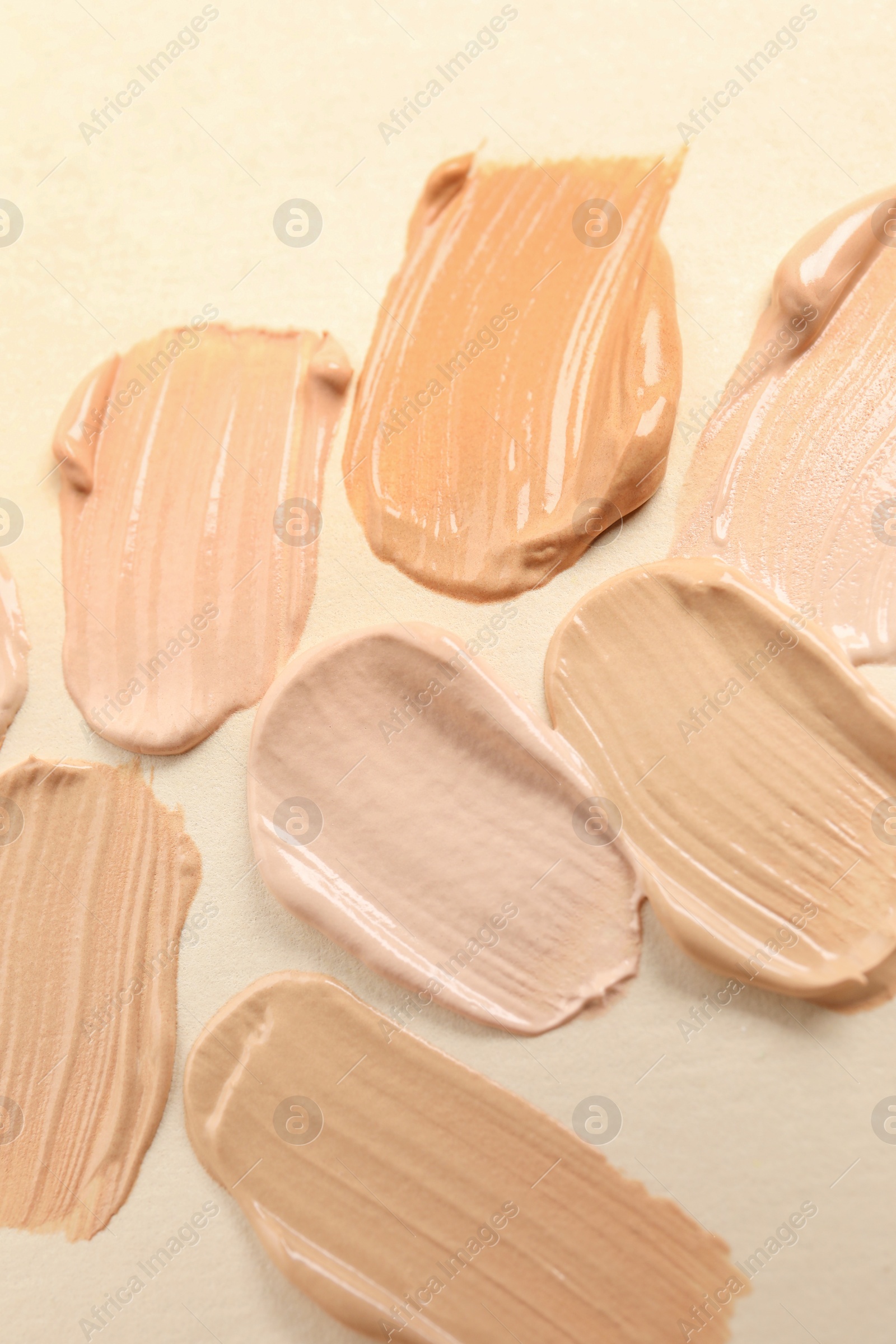 Photo of Samples of skin foundation on beige background, closeup