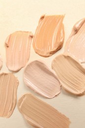 Photo of Samples of skin foundation on beige background, closeup