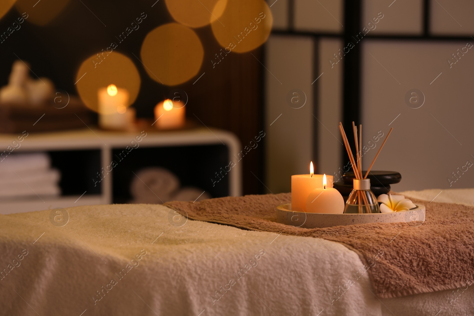 Photo of Burning candles and aromatic reed freshener on table in spa salon, space for text