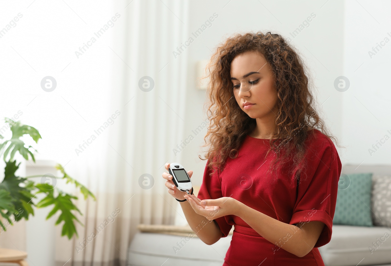 Photo of Young African-American woman using digital glucometer at home. Diabetes control