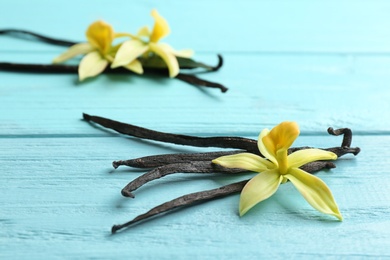 Photo of Vanilla sticks and flowers on wooden background. Space for text