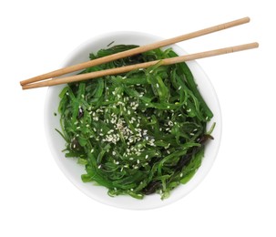 Photo of Tasty seaweed salad in bowl and chopsticks isolated on white, top view