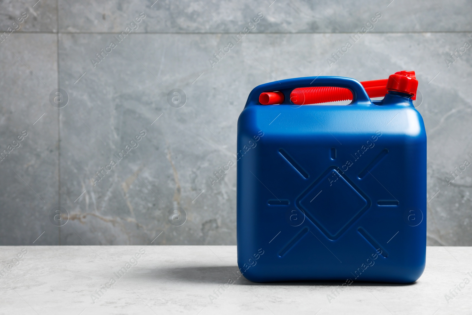 Photo of New blue plastic canister on floor near light grey wall, space for text