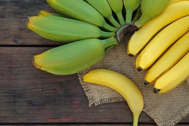 Different sorts of bananas on wooden table, flat lay